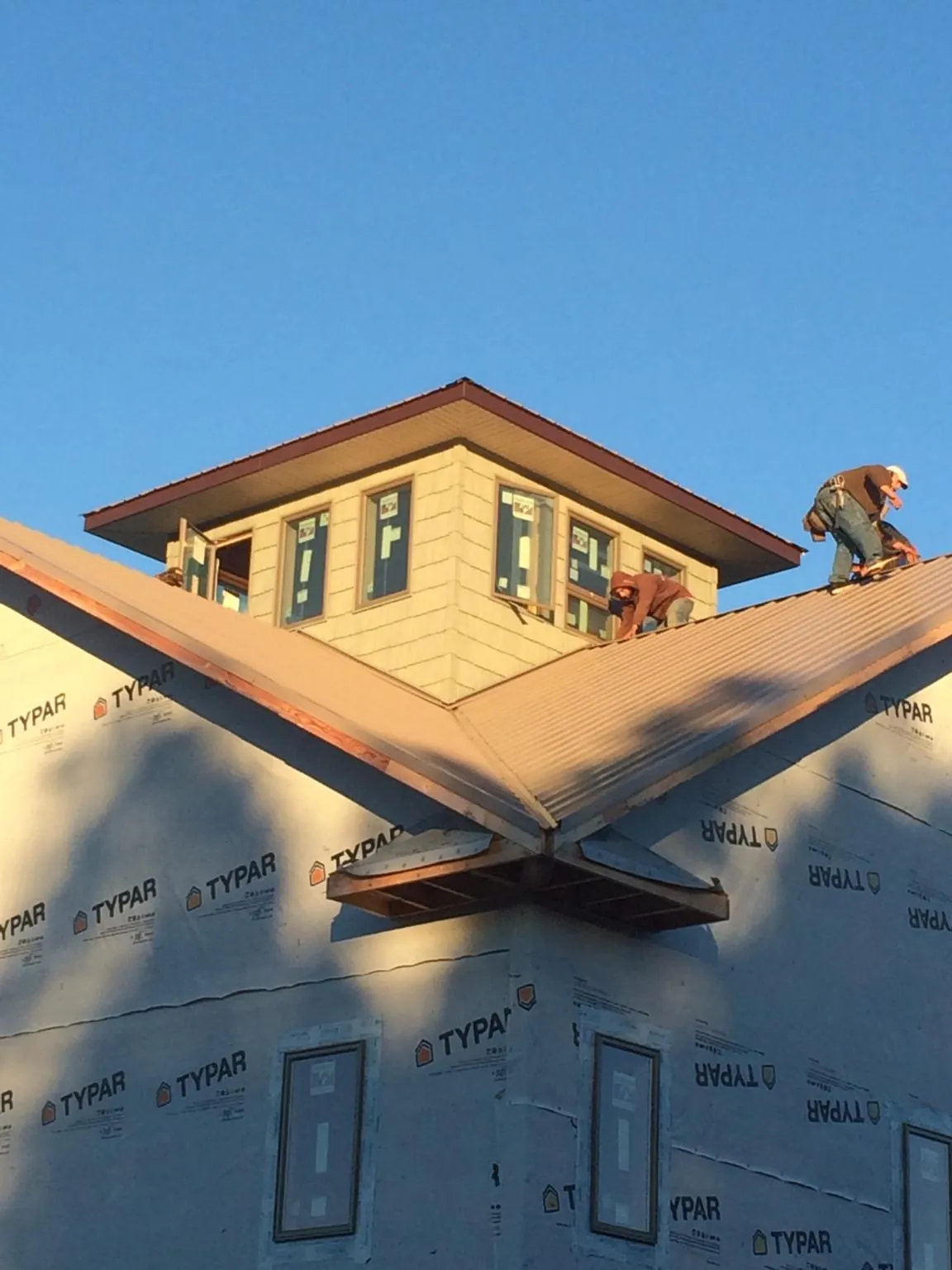 Roofers working around a rooftop cupola on a new metal roof at sunset — Roof Waterproofing in Harrisville by Roofing Brothers